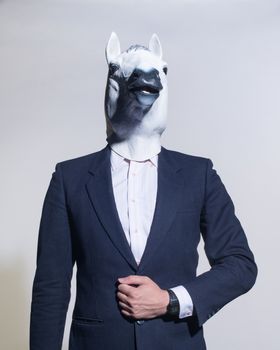 A man in a suit and a horse mask on a light background. Conceptual business background