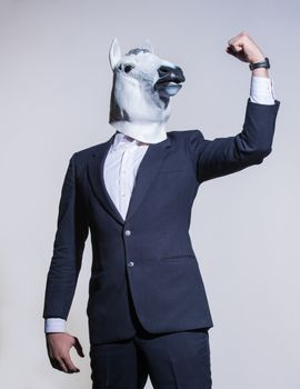 A man in a suit and a horse mask on a light background. Conceptual business background