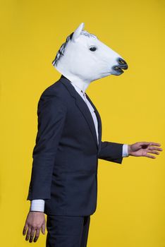 A man in a suit and a horse mask on a yellow background. Conceptual business background