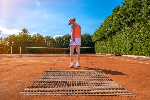 sweeping orange clay on an outdoor tennis court