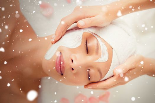 Snow against hands massaging womans face at beauty spa