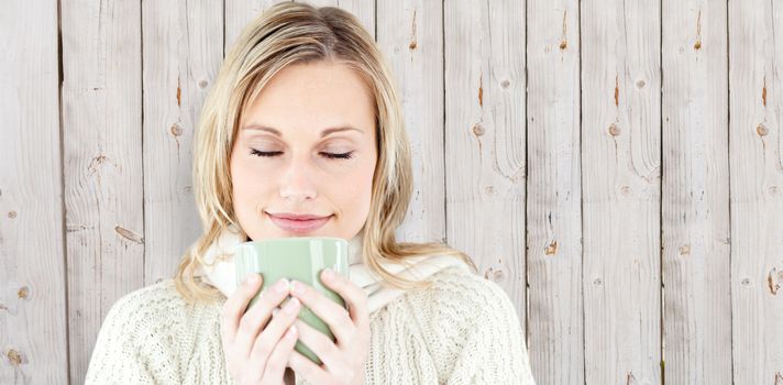 Happy woman enjoying a hot coffee standing  against wooden background