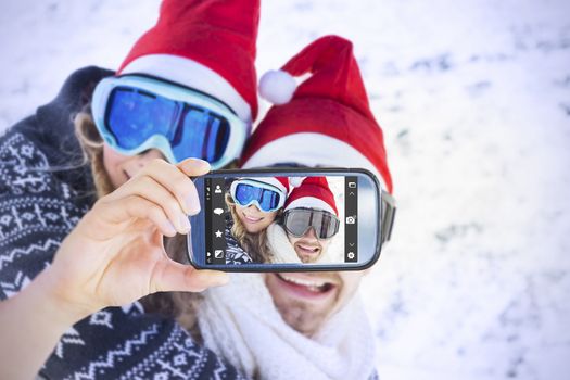 Hand holding smartphone showing against man piggybacking cheerful woman on snow