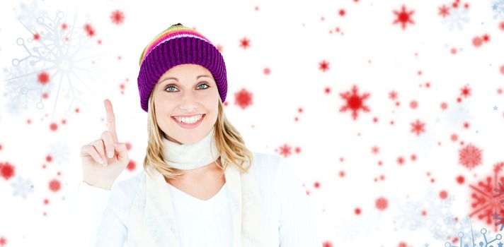 Joyful woman with a colorful hat pointing upwards against snowflake pattern
