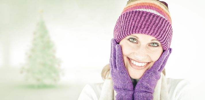 Radiant young woman with cap and gloves in the winter against blurry christmas tree in room