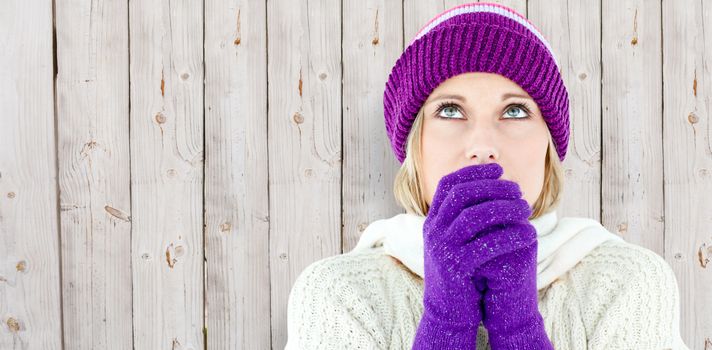 Freezing young woman wearing gloves looking upwards  against wooden background