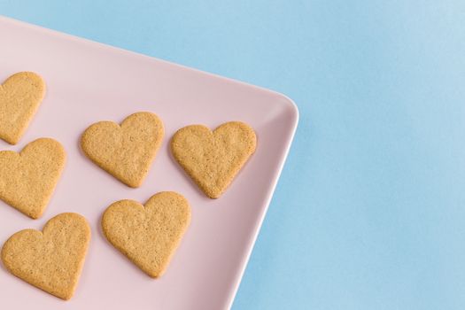 Heart shaped cookies on a pink tray and light blue background. Copy space.