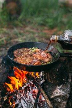 Frying meat in a pan over an open fire with leek. Steak in a pan on a fire. Cooking in nature. Picnic. Grill on fire. Cooking meat in wine.