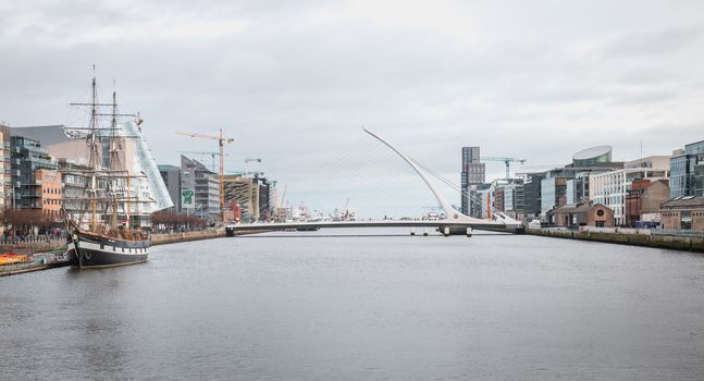 Dublin, Ireland - February 12, 2019: View of the River Liffey in the city center with the replica of the 3-mast sailboat Jeanie Johnston and the Samuel Beckett bridge on a winter day