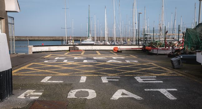 Howth near Dublin, Ireland - February 15, 2019: Keep clear life boat painting on bitumen from a boat care and maintenance area in the harbor on a winter day