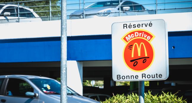 Libourne, France - May 26, 2017: Road sign indicating a place reserved for McDrive customers in the parking lot of a McDonald s restaurant on a spring day