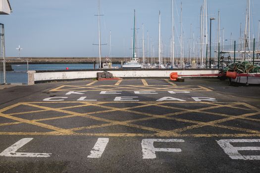 Howth near Dublin, Ireland - February 15, 2019: Keep clear life boat painting on bitumen from a boat care and maintenance area in the harbor on a winter day