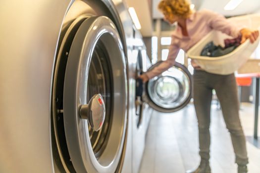 inserting dirty clothes into the washing machine in the laundry room.