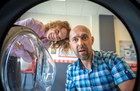 laundry, surprised look men and women into the washing machine or clothes dryer.