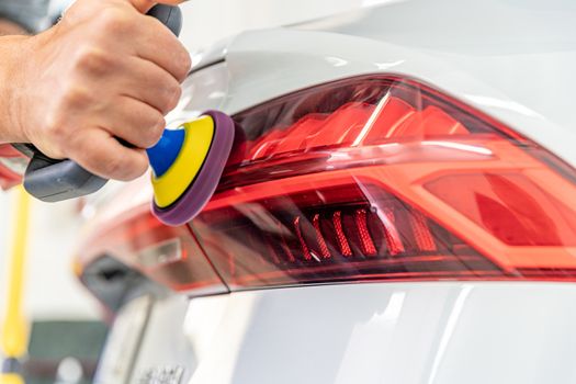 manual polishing of the headlight of luxury cars with the application of protective equipment.