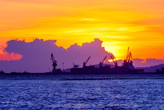 commercial dock with ship and cranes in sunset