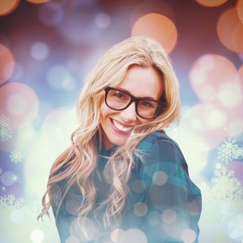 Pretty blonde smiling at camera against snowflake pattern