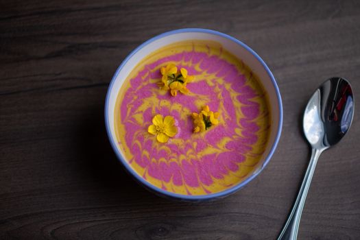 Vegetarian cream pumpkin and beet mix soup decorated with fresh yellow flowers delicious and healthy food