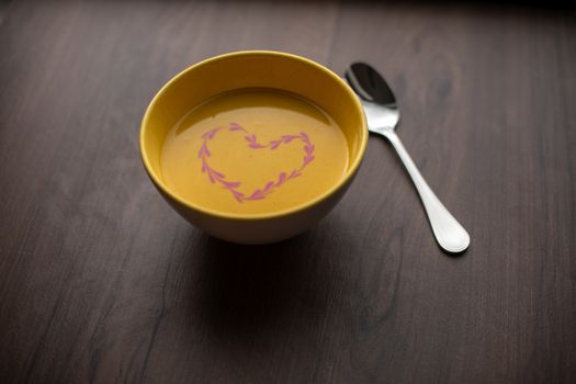 Vegetarian autumn - Pumpkin cream soup with hearth decoration on wooden table