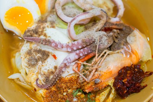 Delicious Thai food. Noodle with hot and sour seafood (prawn and squid) soup with slice boiled egg and vegetable in brown bowl at cafe and restaurant.