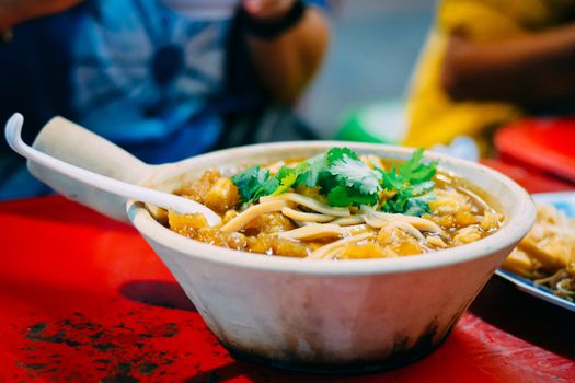 Braised fish maw in red gravy in white ceramic bowl served in restaurant at China town in Thailand. Selective Focusing.