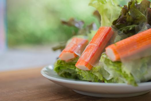 Crab stick in salad roll on white dish. Healthy food concept.