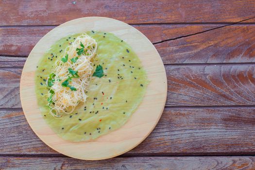 Thai food. Vermicelli rice wrap with coriander and spicy sauce on round wooden tray.