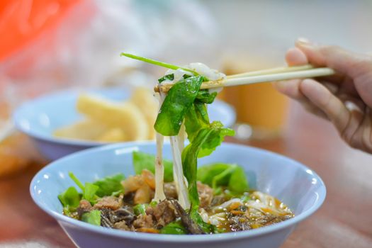 Thai local food Northen of Thailand. Eattind rice noodles with spicy pork sauce with chopsticks. Selective focus.