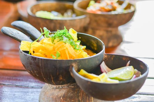 Northern Thai curry noodles with chicken serve in coconut shell on wooden table. Delicious Thai food.