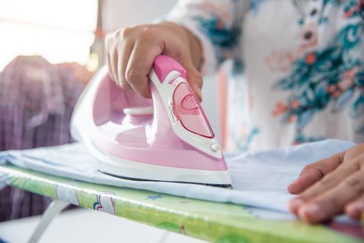 Close up of woman ironing clothes on ironing board