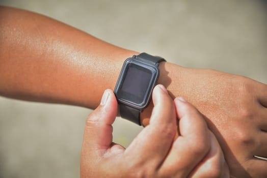 Closeup of hands and wrist with smart watch screen, smartwatch touching button and touchscreen on active sports activity