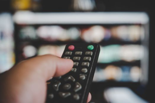 Watching  television, with a tv remote control in the hand 
