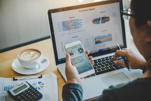 Businessmen use smartphones and laptop to connect and find information in office