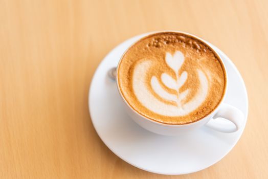 Latte coffee in glass placed on wooden floor.