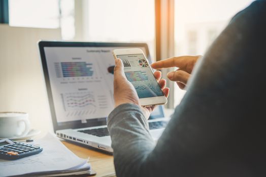 Businessmen use smartphones and laptop to connect and find information in office