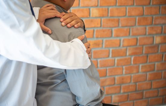 The doctor is checking the patient who is a businessman with a shoulder injury.