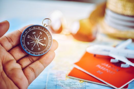 Tourists hold a compass and locate a place on a world map.