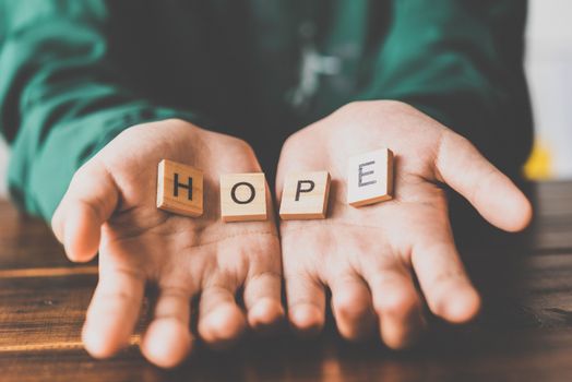 Human hands open palm of Christian and has the letter "HOPE" in hand