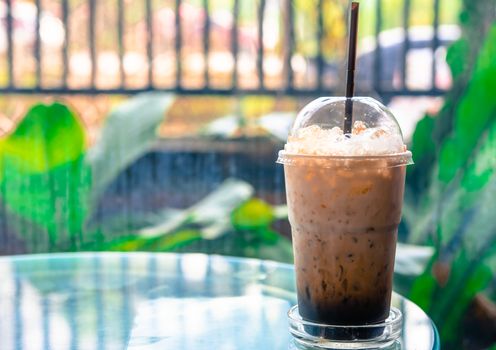 Ice coffee in a tall glass on a  table. Cold summer drink in coffee shop