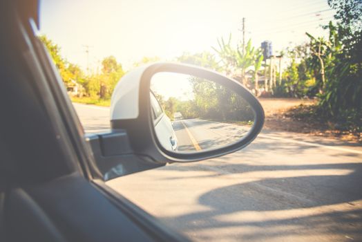 Rear-view mirror car in the reflection forest and long roadway