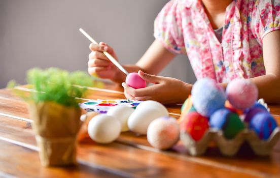 young girl painting Easter eggs for eastertime at home