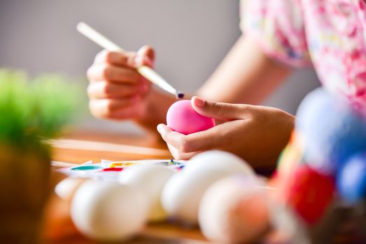 young girl painting Easter eggs for eastertime at home