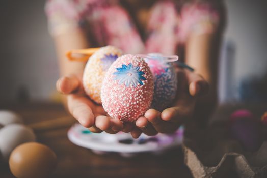 young girl painting Easter eggs for eastertime at home