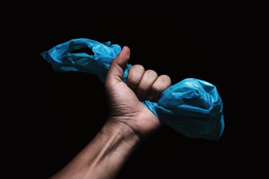 blue plastic bag in hand with dark background