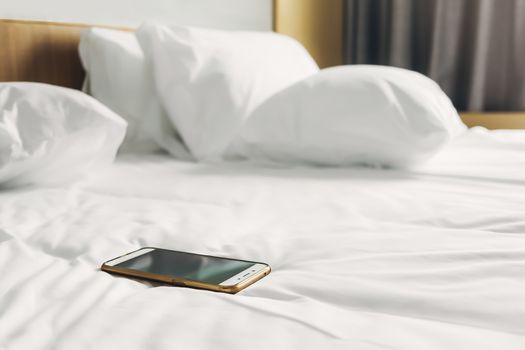 cellphone on white bed sheets in bedroom at morning