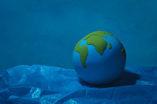 clay earth floating on blue plastic ocean