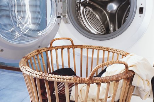 clothes in the basket and washing machine in laundry room