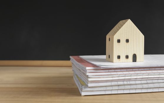 house model on a notebook pile with a blackboard background. distant studying class preparation for homeschool education.staying and learning from home during school shutdown because of covid-19.