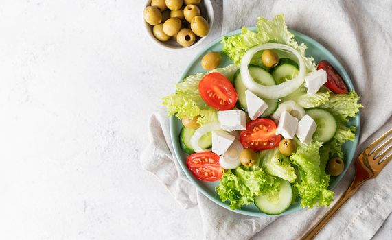 Healthy food. Top view of greek salad with olives and fresh vegetables on blue plate with copy space