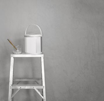 paint bucket and brush on ladder for painting the gray wall